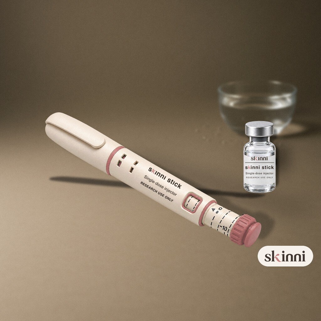 A clear Acetic Acid 0.6% research vial on a coloured plaster ledge, with botanicals beside it