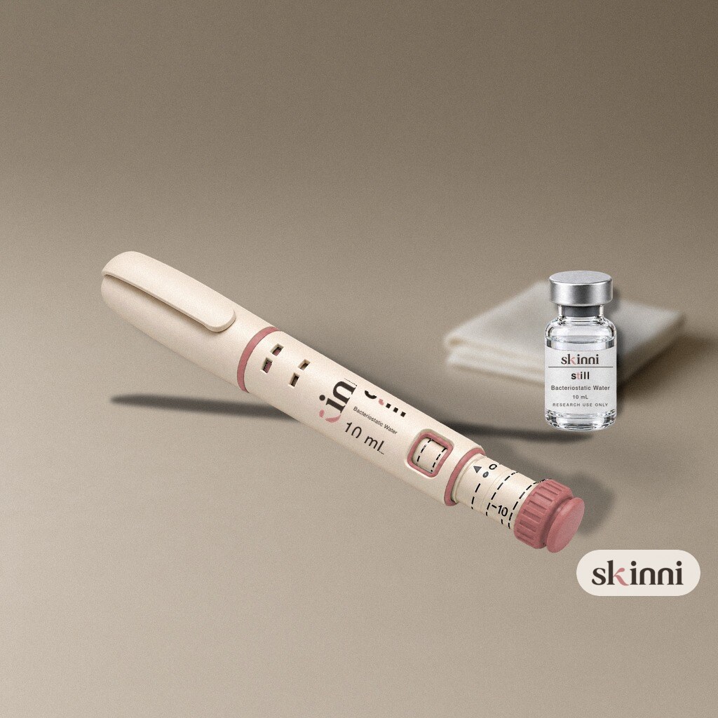 A clear Bacteriostatic Water research vial on a coloured plaster ledge, with botanicals beside it