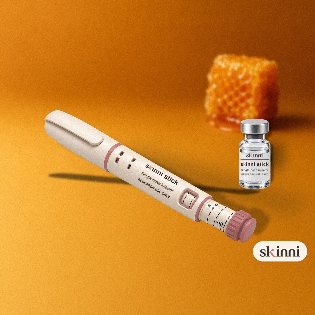 A clear Kisspeptin-10 research vial on a coloured plaster ledge, with botanicals beside it