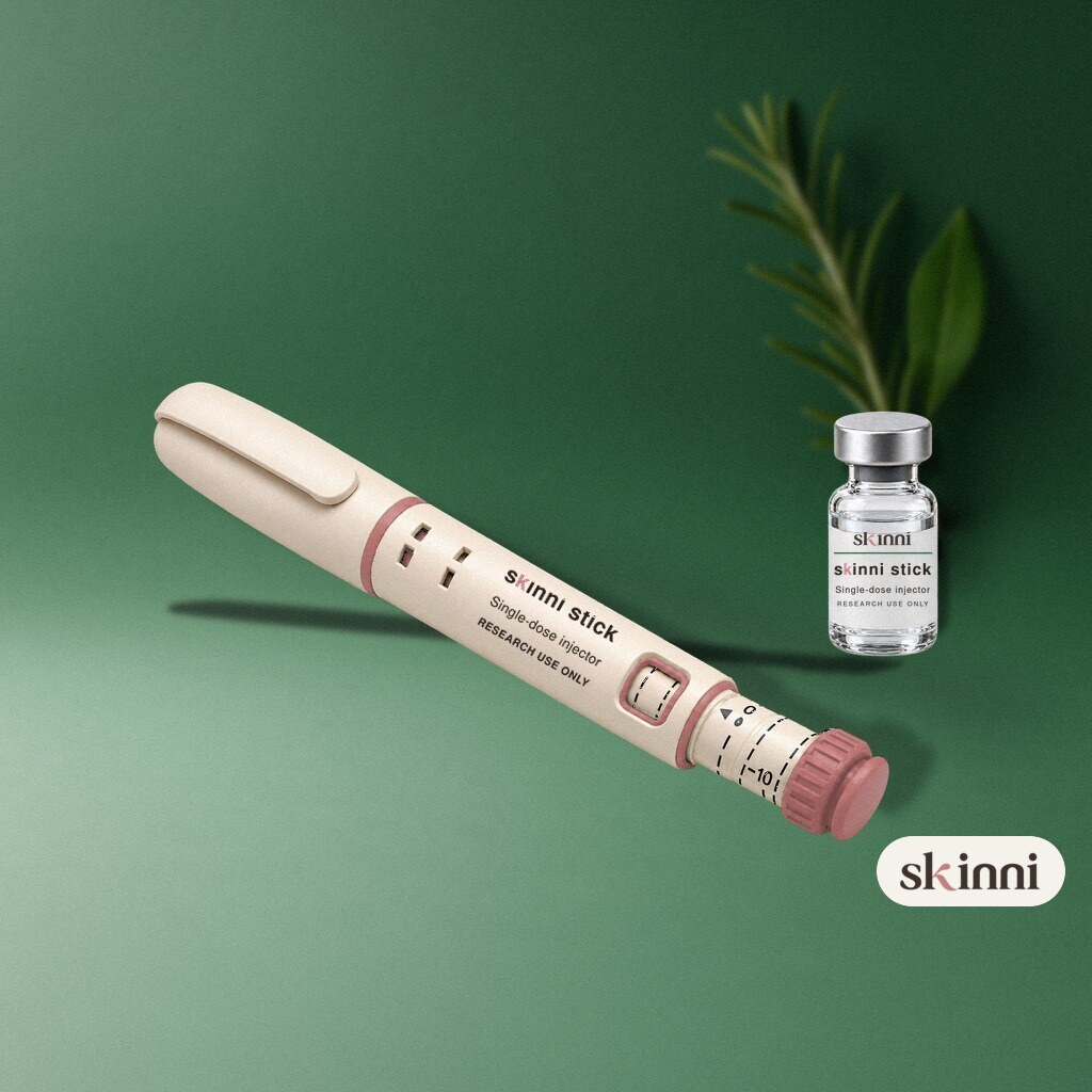 A clear KLOW Blend research vial on a coloured plaster ledge, with botanicals beside it