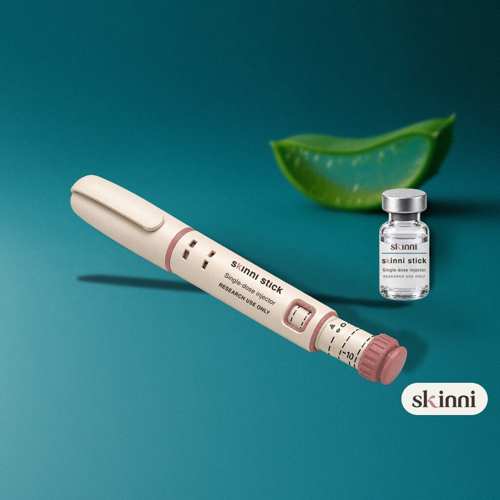 A clear L-Glutathione research vial on a coloured plaster ledge, with botanicals beside it