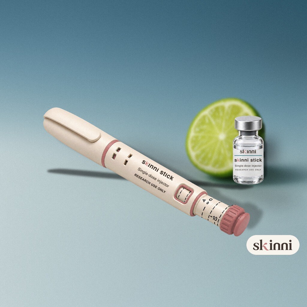 A clear NAD+ research vial on a coloured plaster ledge, with botanicals beside it