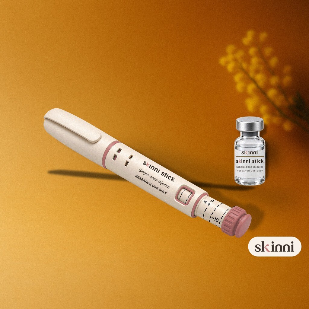 A clear Sermorelin research vial on a coloured plaster ledge, with botanicals beside it