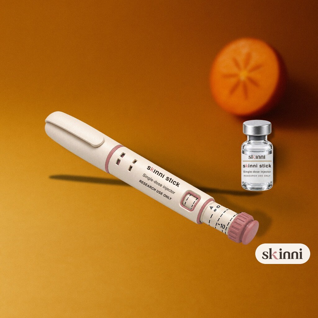 A clear Tesamorelin research vial on a coloured plaster ledge, with botanicals beside it