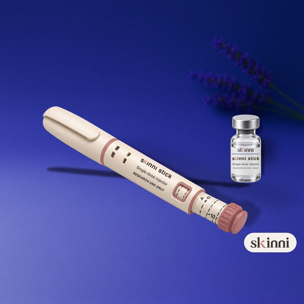 A clear VIP research vial on a coloured plaster ledge, with botanicals beside it
