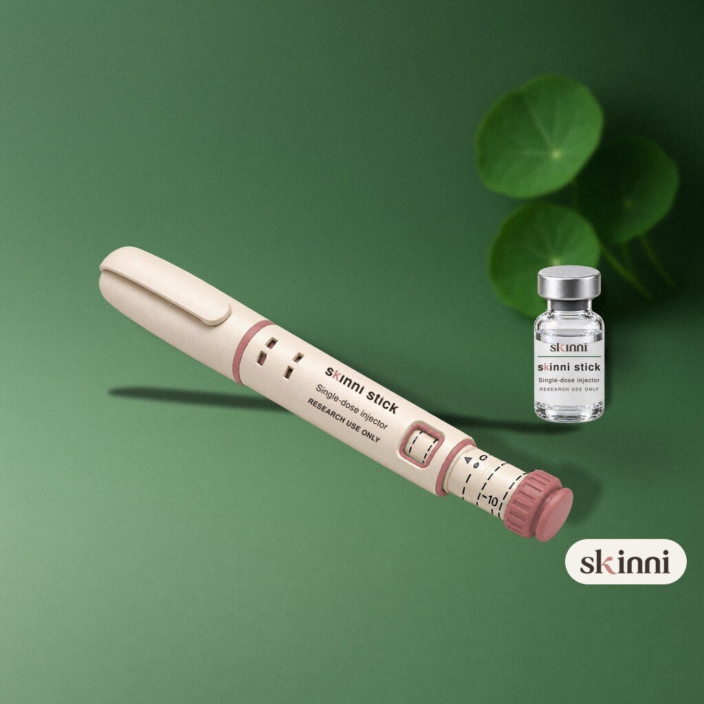 A clear Wolverine Blend research vial on a coloured plaster ledge, with botanicals beside it